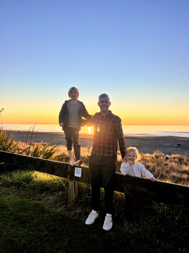 Mark with his two children at sunset on a Taranaki beach